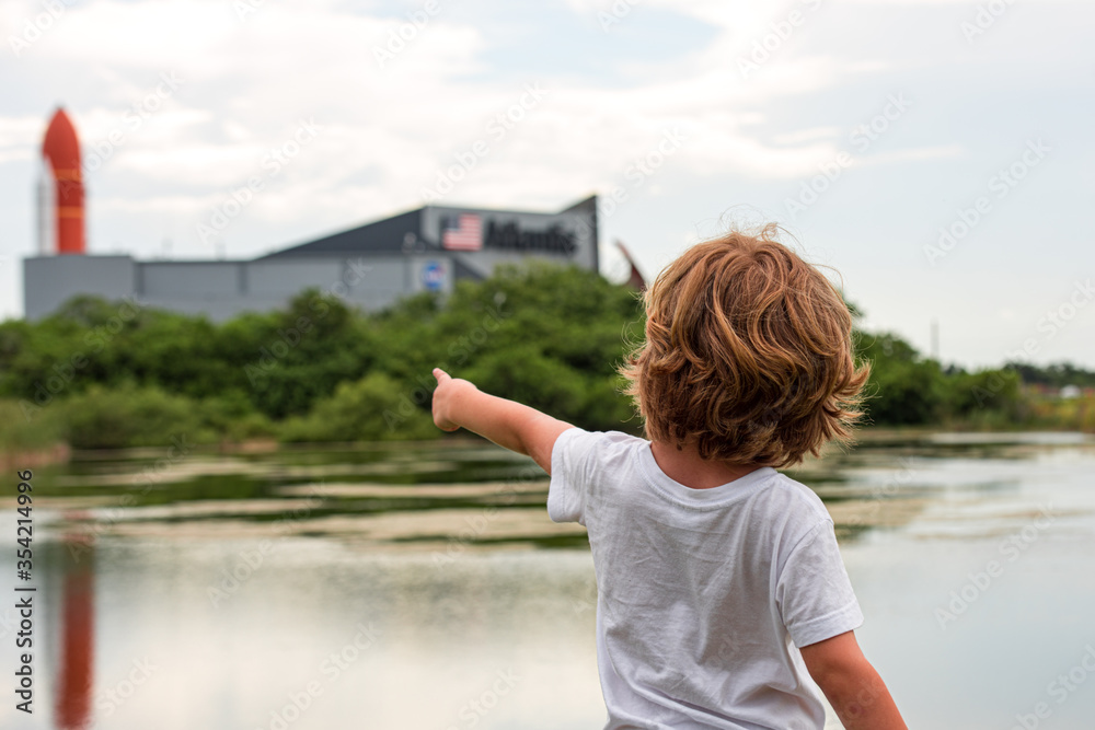 Cape Canaveral, FL, USA - MAY 27, 2020: The big dream of space. The child points a finger at the space center. NASA. Kennedy Space Center Visitor Complex in Cape Canaveral, Florida, USA. - obrazy, fototapety, plakaty 