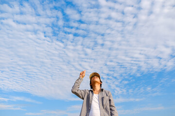 Asian men are watching and pointing to the sky.Men wear gray shirts and wear striped hats.Look up and look at copy space