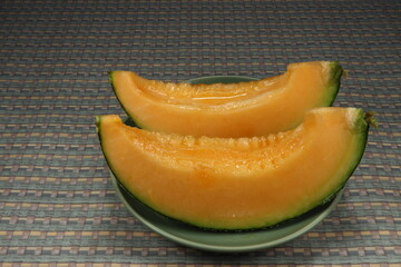 Piece of sliced ripe orange melon (Japanese melon, cantaloupe) on the plate. Famous juicy fruit in Asia restaurant. Tropical fruit with high vitamin and fiber. 