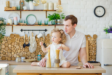 Small child girl playing in the kitchen at the table. Happy family father, child, daughter preparing food at home. A celebration in honor of father's Day. Parenting a child