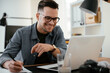 © JustLife - Young businessman using laptop in his office.  Handsome man working in office.