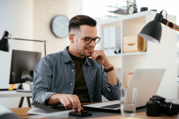 Young businessman using laptop in his office.  Handsome man working in office.	