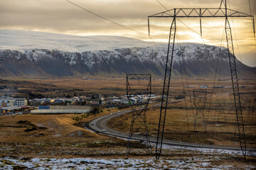 Wall Mural - High voltage electricity poles and beautiful scenery from high in the morning, mountains and villages In winter. The grass is dark yellow in the countryside of Iceland.