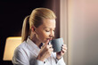 © JustLife - Businesswoman relaxing in hotel room. Young beautiful woman drinking coffee.