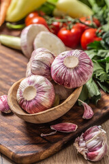 Wall Mural - Garlic heads in wooden bowl surrounded by vegetables