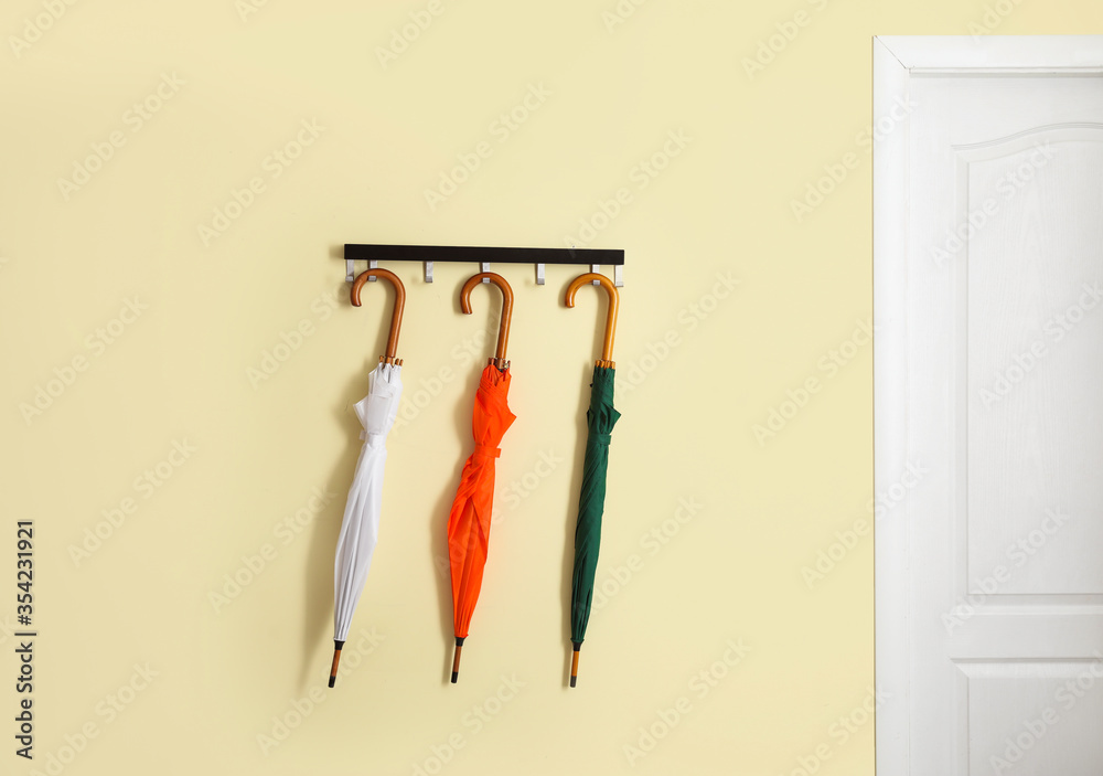 Stylish umbrellas hanging on wall in interior of hall