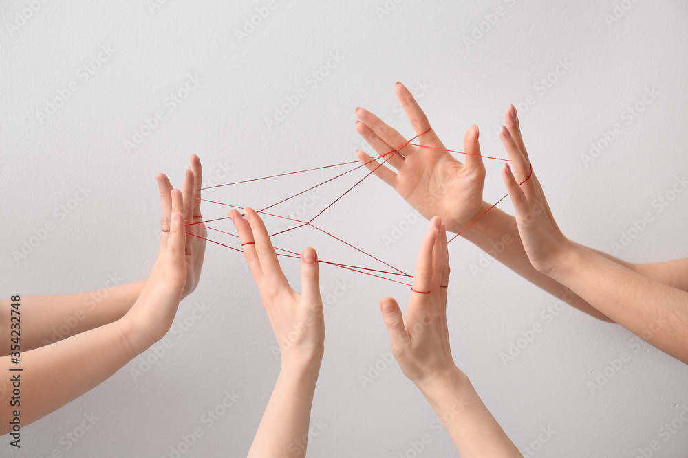 Hands tied with red thread on light background. Unity concept - obrazy, fototapety, plakaty 