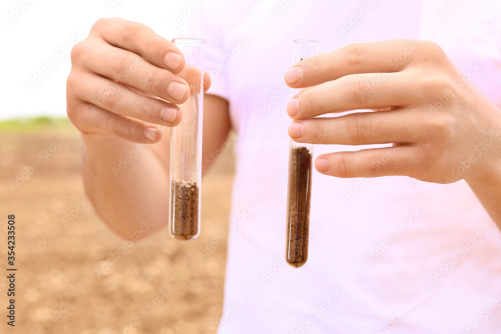 Agronomist studying samples of soil in field, closeup