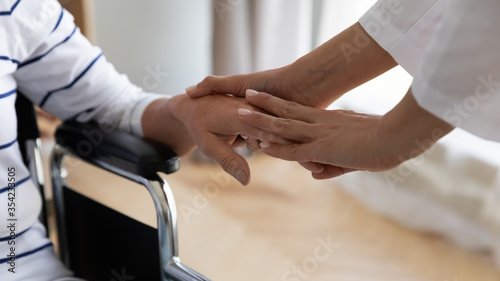 Fotografía Disabled elderly woman sitting in invalid carriage her palm holding stroking caring nurse close up image