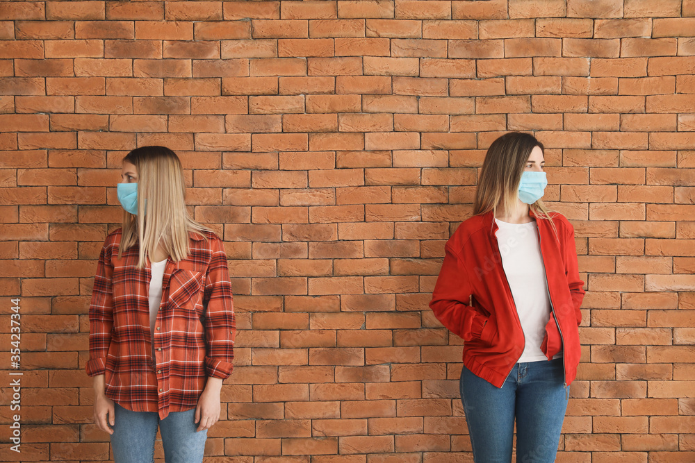 Young women near brick wall. Concept of social distance during coronavirus epidemic