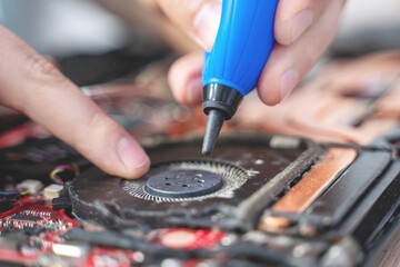 Wall Mural - man cleans a laptop with a special tool for blowing dust cooling system. Repair and service laptops and PC Advertisement of repair service for electronics and devices