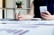© Orathai - Office girl is sitting at a desk and use telephone calculating financial graph that show results In the office