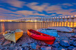 Colorful dinghy boats on a sandy beach along the bay with the San Diego–Coronado Bridge in the distance at night.