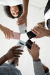 © fizkes - Close up bottom view diverse people using phones, standing in circle, employees holding smartphones in hands, looking down at screen, social media addiction, chatting, shooting video or photo