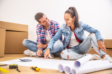 Happy couple moved in to a new house having fun while planning on the interior design