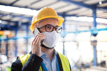 Wall Mural - Technician or engineer with protective mask and telephone in industrial factory.