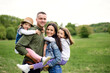 © Halfpoint - Happy family with two small daughters standing outdoors in spring nature.