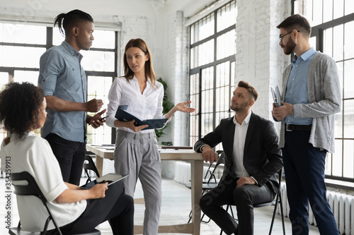 Fotomural Confident businesswoman mentor leading briefing, teaching diverse employees, sta
