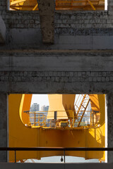 Yellow orange crane chassis in the sunny day. Brand new high lifter looking from the building around the river. The building along side the river in the background. Industrial machine and the building