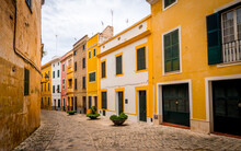 Quaint Narrow Alley With Colorful Painted Houses In The Old Town Of Ciutadella With Vanishing Point To The Left Side