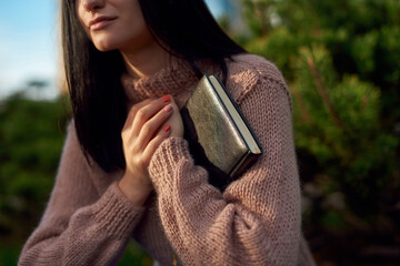 Pretty woman carefuly holding paper notebook to her heart