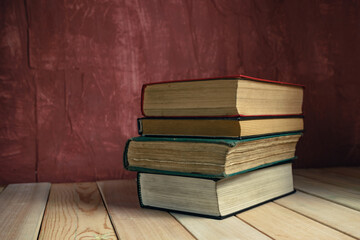 Poster - Old books on a old wooden table. Beautiful Red wall background.