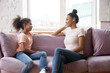 © fizkes - African family spend time at home mother sitting on couch with pre-teen daughter women talking smiling enjoy pleasant honest conversation. Communication and understating between two generation concept