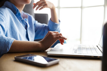 Sticker - Cropped image of woman working with laptop and cellphone while sitting