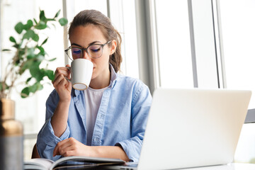 Sticker - Image of woman working with laptop and drinking tea while sitting