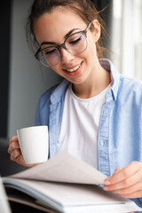 Poster - Image of woman reading book and drinking coffee while sitting at table