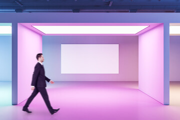 Poster - Businessman walking in gallery interior with blank poster on wall.