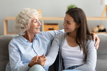 Elderly loving grandmother sitting with adult granddaughter holding her hand embracing enjoy communication, having warm relations, multi-generational family relatives women heart-to-heart talk concept