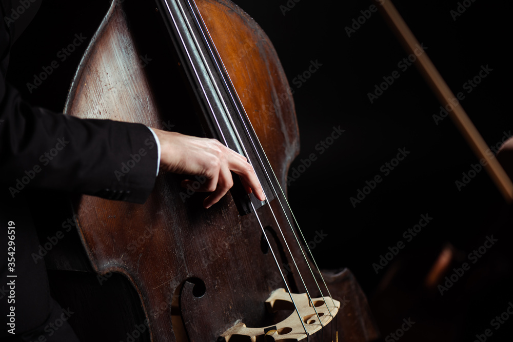cropped view of musician playing on contrabass on dark stage - obrazy, fototapety, plakaty 