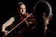 © LIGHTFIELD STUDIOS - happy professional musicians playing classical music on violins on dark stage