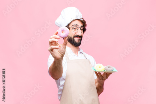 Fotografía young crazy baker man confectionery concept against pink wall