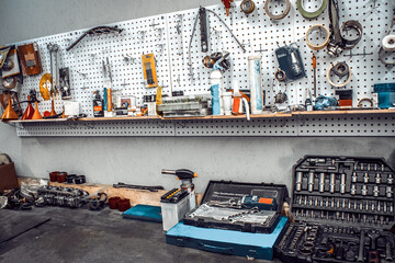 Wall Mural - Maintenance station, motorcycle and car repair, mechanical equipment on the wall, a set of tools in the workshop. Garage with a large workbench with professional wrenches in drawers and spare parts.