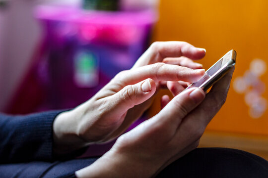 Unrecognizable female hand using a smartphone. Woman texting with his smartphone in house.