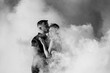 © omelnickiy - guy and a girl in black clothes hug inside a  smoke