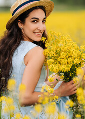 a young woman sits among a field of yellow flowers, smiles, holds a bouquet in her hands, looks at the camera. portrait of a young woman with dark skin and brown eyes