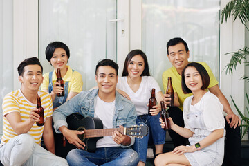 Wall Mural - Cheerful Vietnamese young people drinkign beer and singing song at party