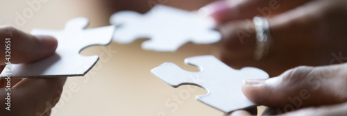Fotografía Close up photo hands of multi ethnic people hold diverse pieces of puzzle, team assembling jigsaw joining fragments, teamwork, search find solution concept