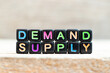 © bankrx - Black bead with color letter in word demand supply on wood background