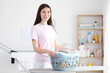 © White bear studio  - Young housewife in the laundry room. Laundry, household chores