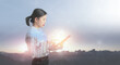 © jayzynism - Businesswoman holding with tablet pc against high tech overlooking the view of landscape.