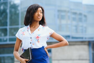 Beautiful black woman using tablet computer in urban background. Successful woman concept.