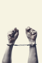 Two Hands On A White Background With Fingers Gathered Towards Fists With Handcuffs On Hands