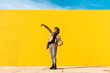 © VISTA by Westend61 - Young man dancing in front of yellow wall, taking selfies