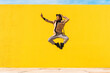 © VISTA by Westend61 - Young man dancing in front of yellow wall, taking selfies