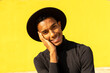© VISTA by Westend61 - Portrait of young man, wearing black in front of yellow wall, hand on face
