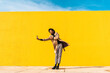 © VISTA by Westend61 - Young man dancing in front of yellow wall, taking selfies
